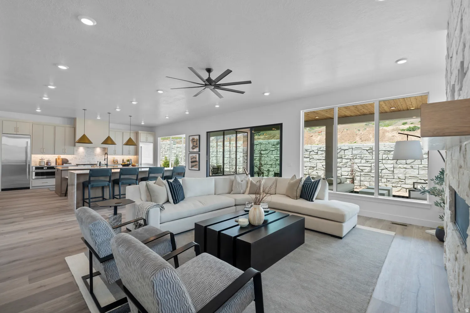 Living room featuring ceiling fan, light wood-type flooring, a stone fireplace, and recessed lighting