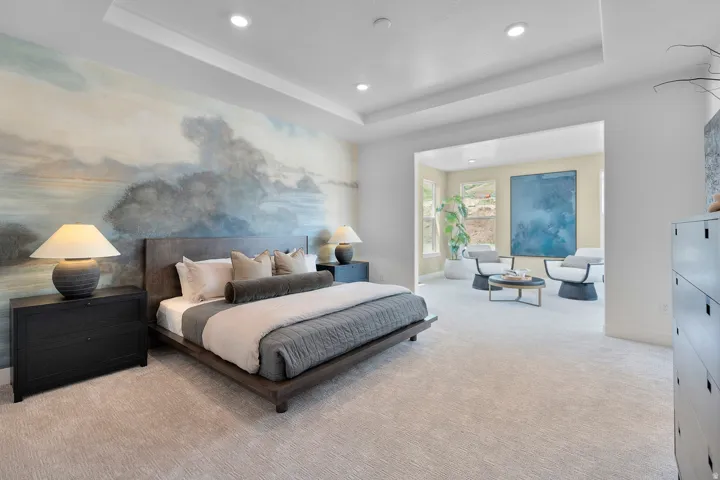 Bedroom with light carpet, a raised ceiling, and recessed lighting