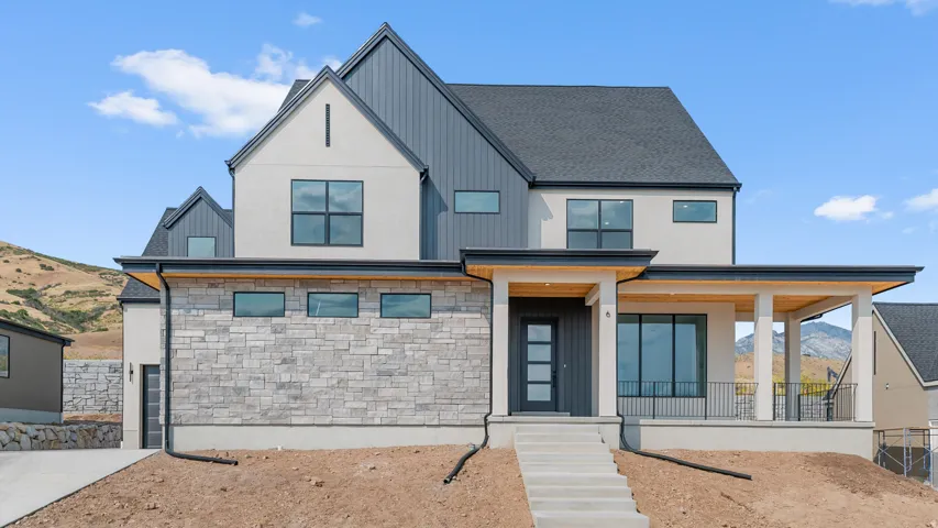 View of front of home with stone siding, a mountain view, a porch, and a shingled roof