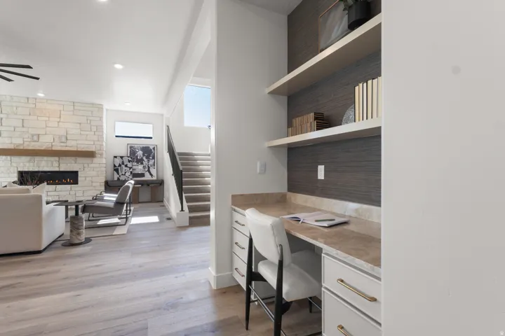 Office featuring built in desk, light wood-style floors, a fireplace, recessed lighting, and ceiling fan