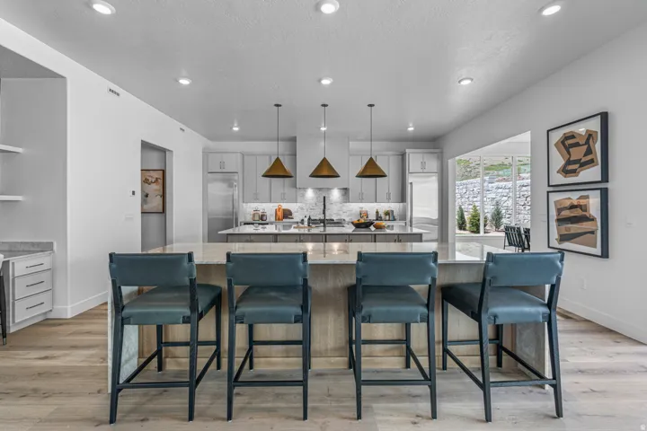 Kitchen with built in fridge, light wood-style flooring, light stone counters, a breakfast bar area, and tasteful backsplash