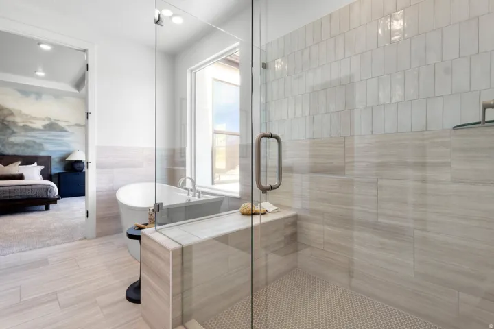 Full bathroom featuring tile walls, a stall shower, a freestanding tub, ensuite bathroom, and recessed lighting