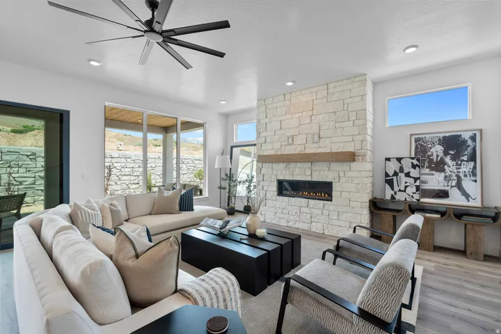 Living room with wood finished floors, a fireplace, ceiling fan, and recessed lighting