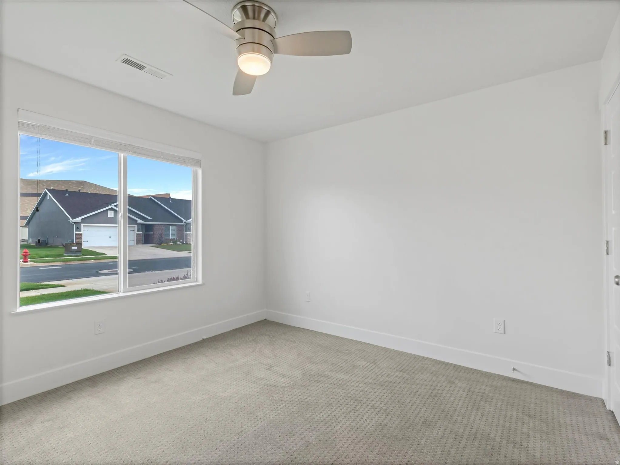 Unfurnished room with light colored carpet and a ceiling fan