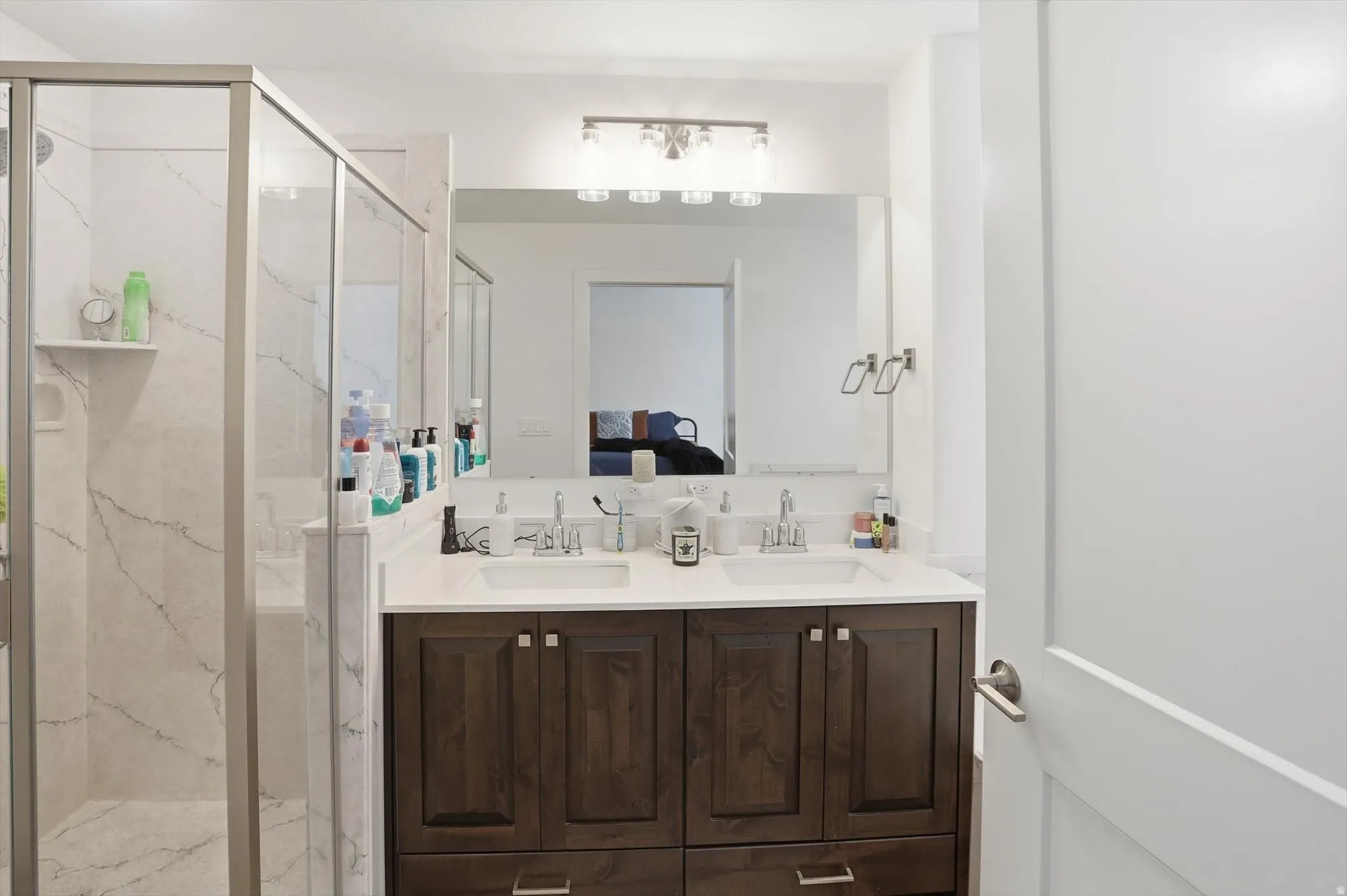 Ensuite bathroom featuring double vanity and a marble finish shower