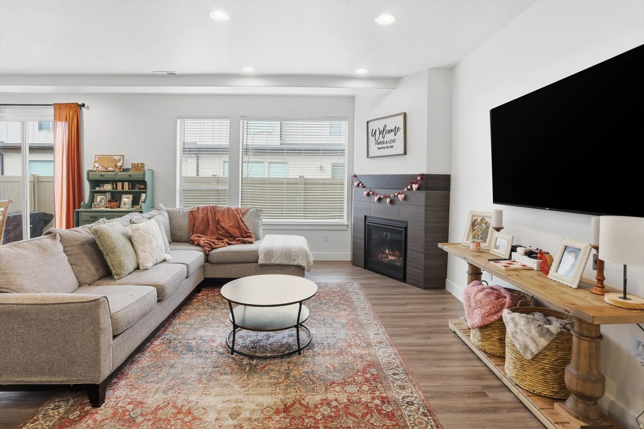Living room with a glass covered fireplace, recessed lighting, and wood finished floors