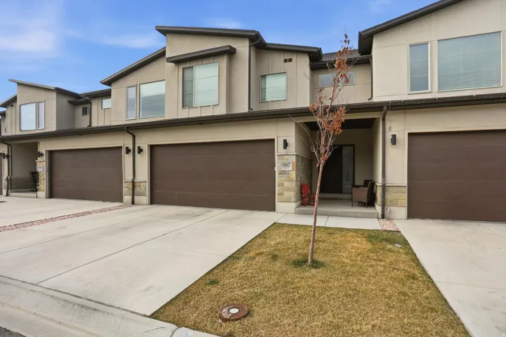 View of front of home featuring stone siding, a garage, and stucco siding