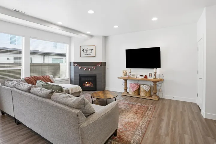 Living area featuring wood finished floors, a glass covered fireplace, and recessed lighting