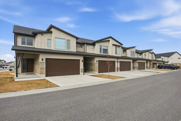 Contemporary house featuring stucco siding, stone siding, a garage, and concrete driveway