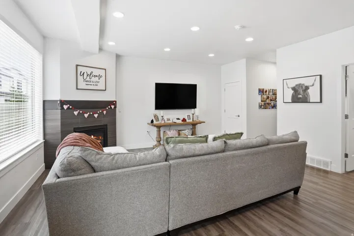 Living room with wood finished floors, a lit fireplace, and recessed lighting
