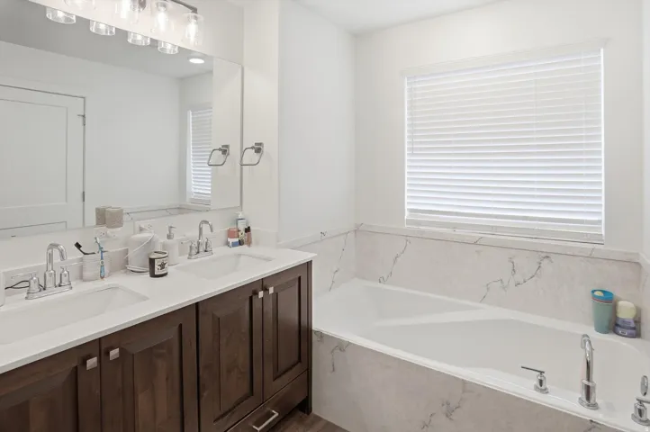 Full bath with double vanity, a bath, and plenty of natural light