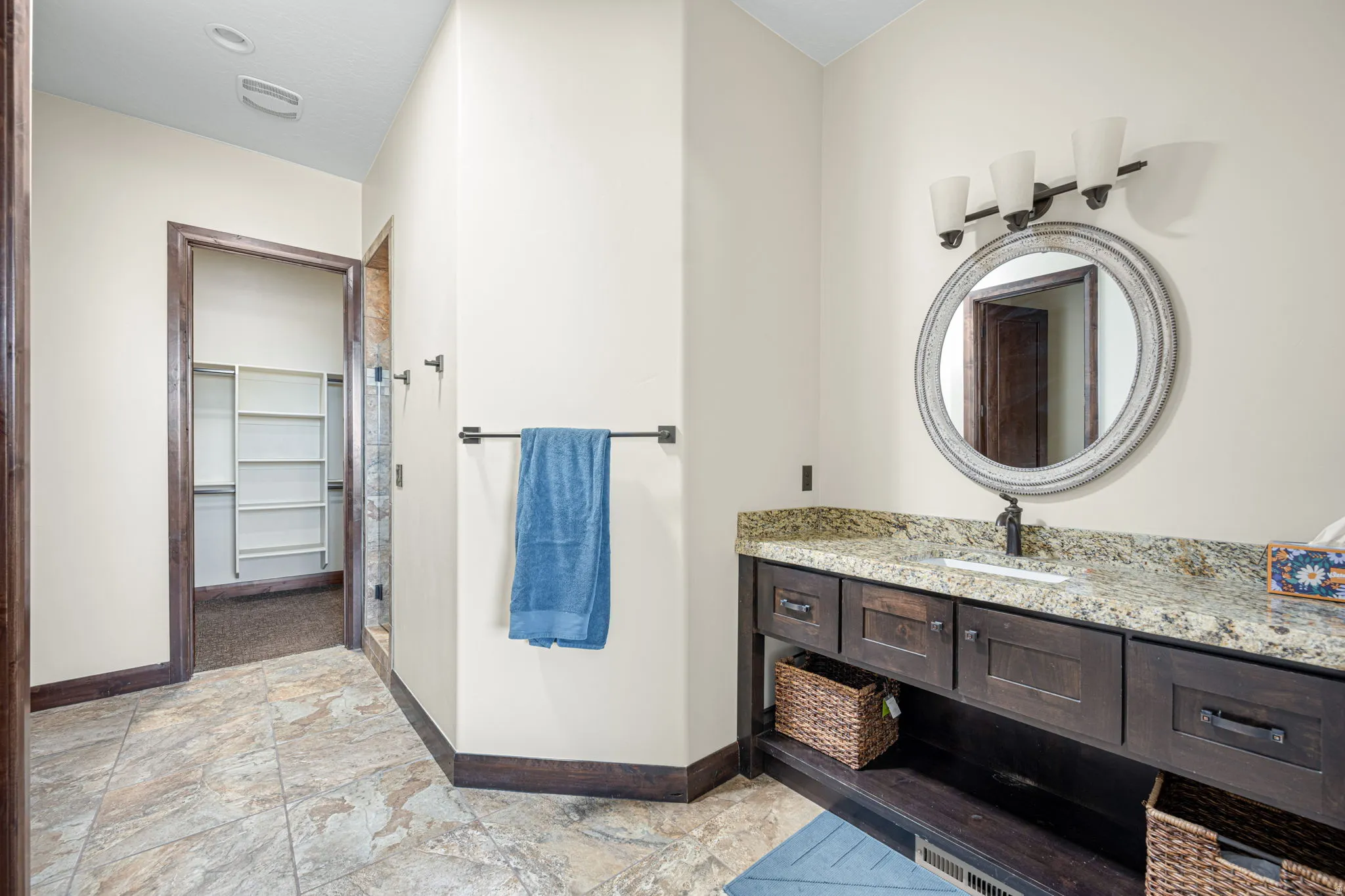 Full bathroom featuring vanity, a spacious closet, a shower stall, and light stone finish floors