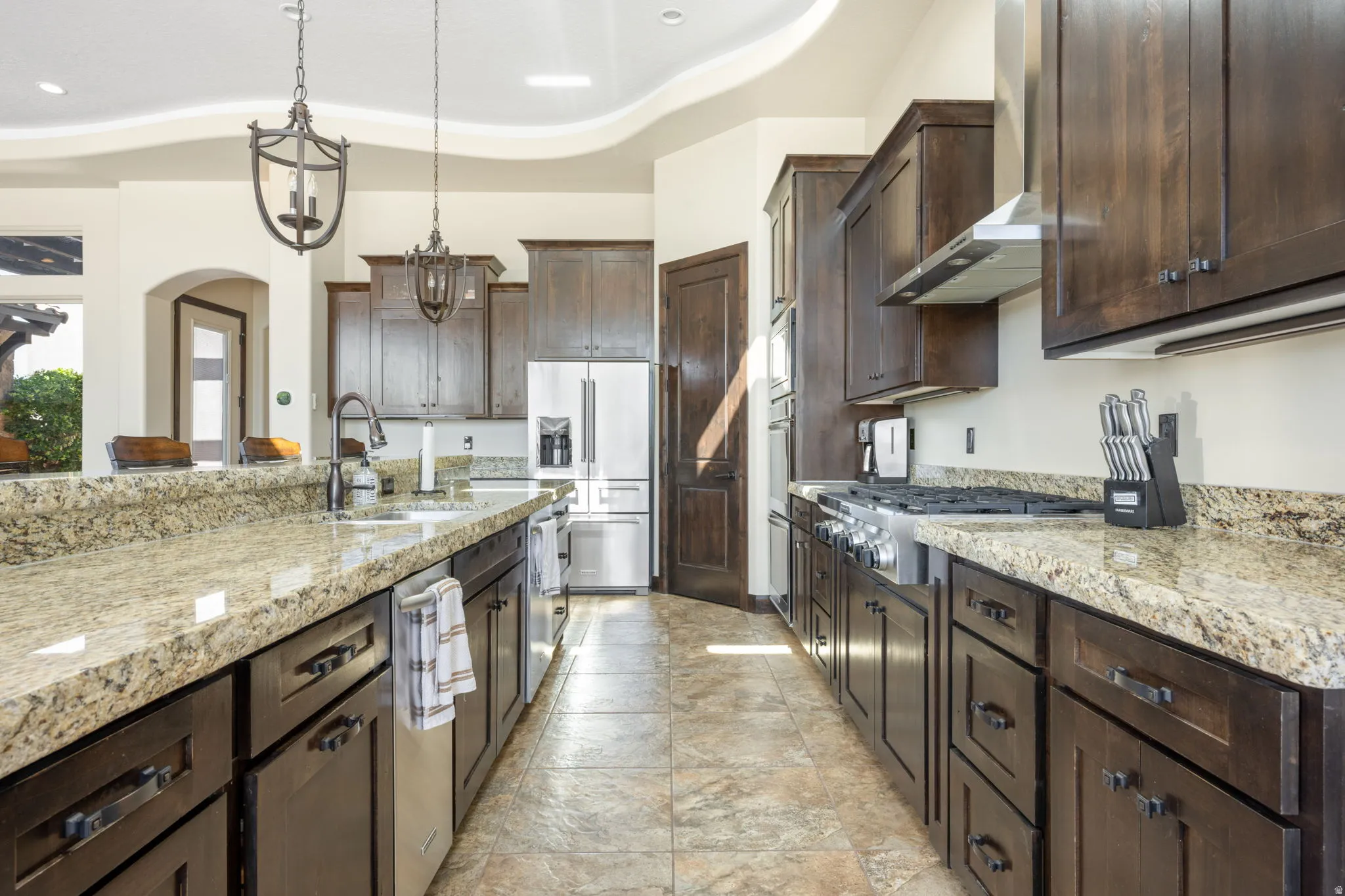 Kitchen featuring dark wood finish cabinetry, light stone countertops, stainless steel appliances, and a tray ceiling