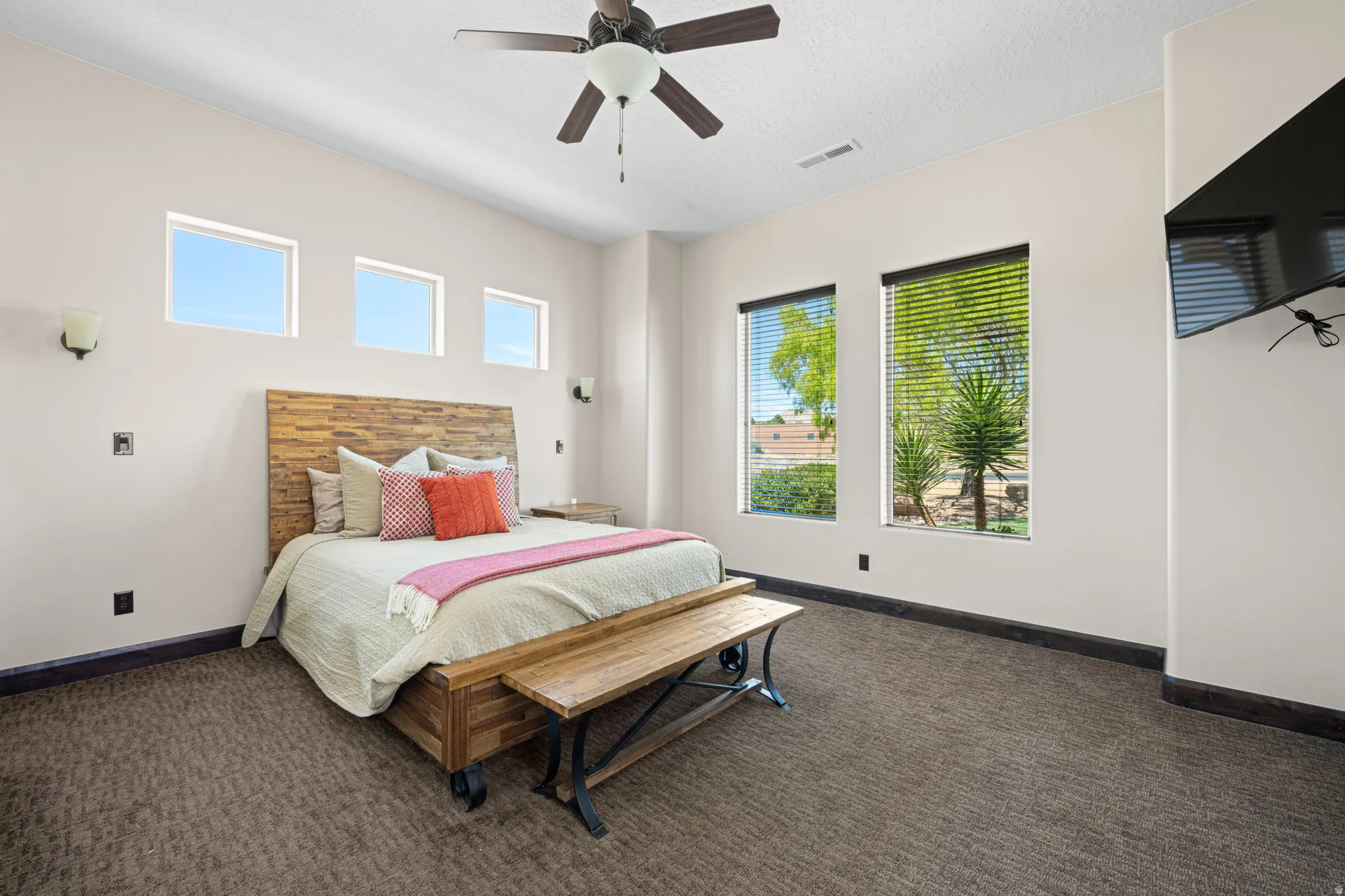 Bedroom with dark colored carpet, ceiling fan, and a textured ceiling