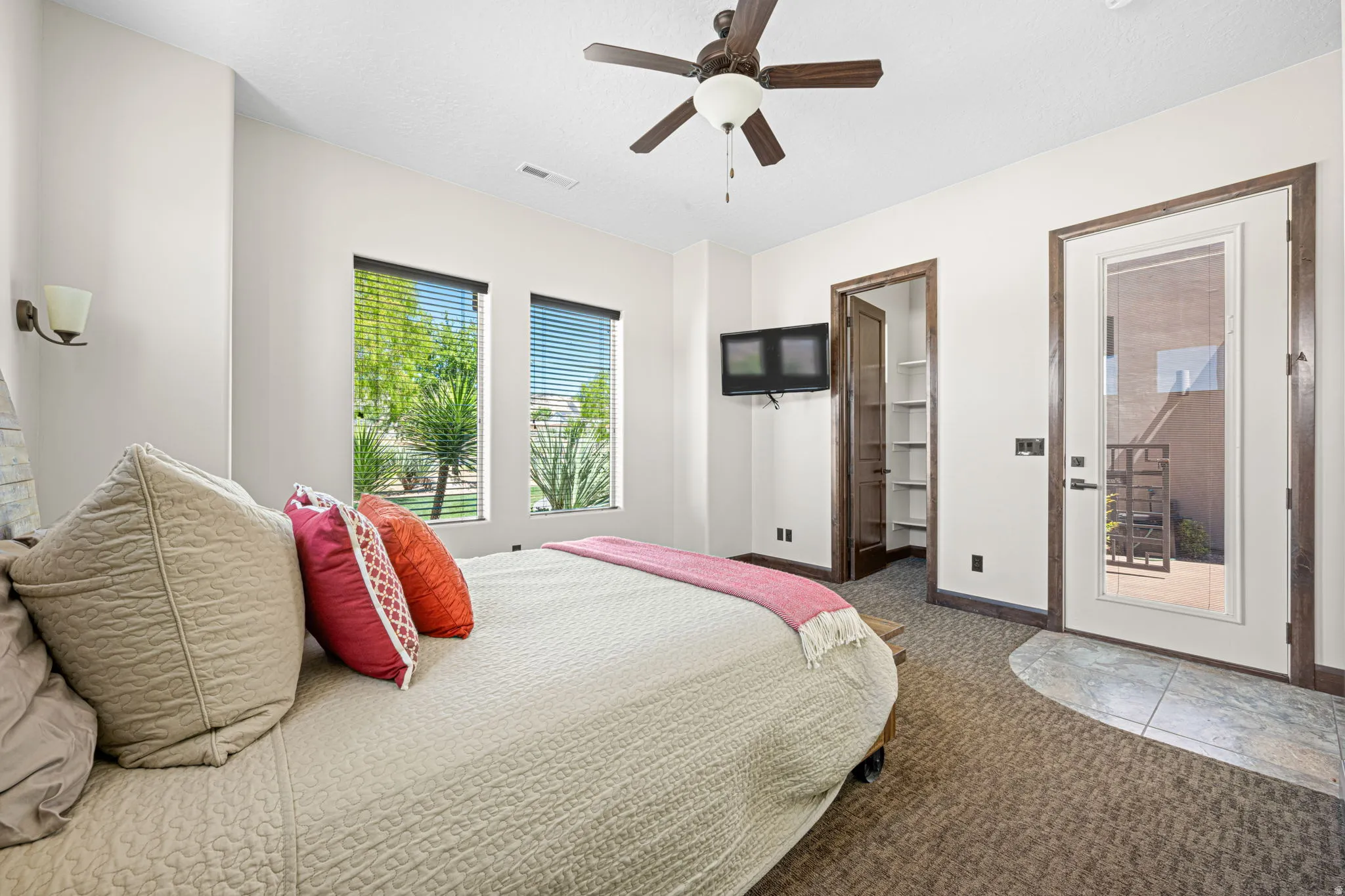Carpeted bedroom with ceiling fan and access to exterior