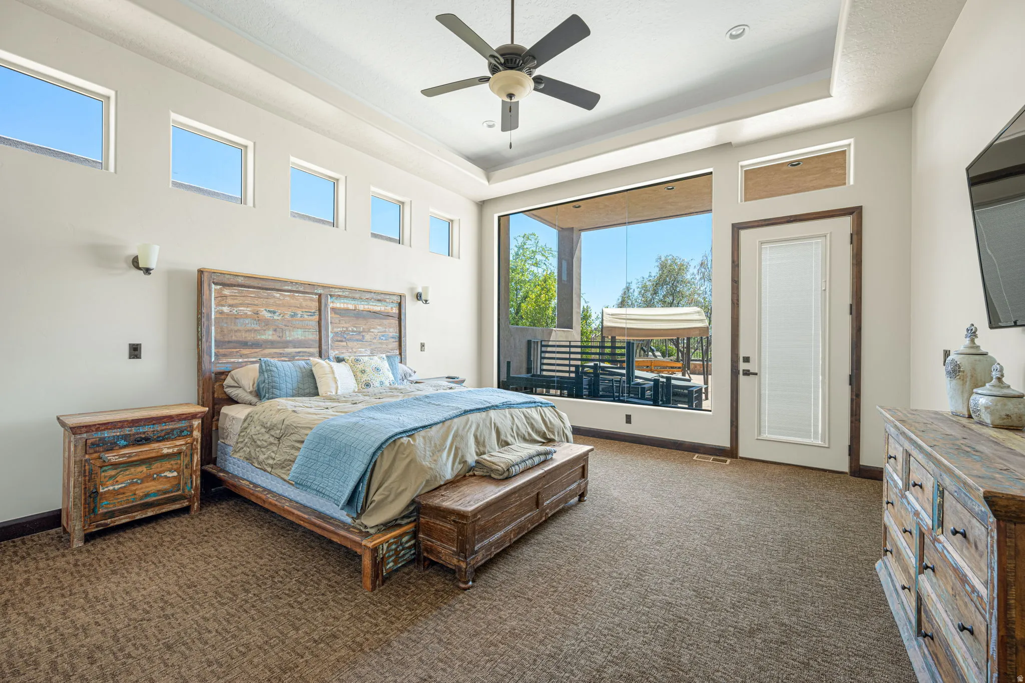 Bedroom featuring a tray ceiling, a ceiling fan, dark colored carpet, and access to outside