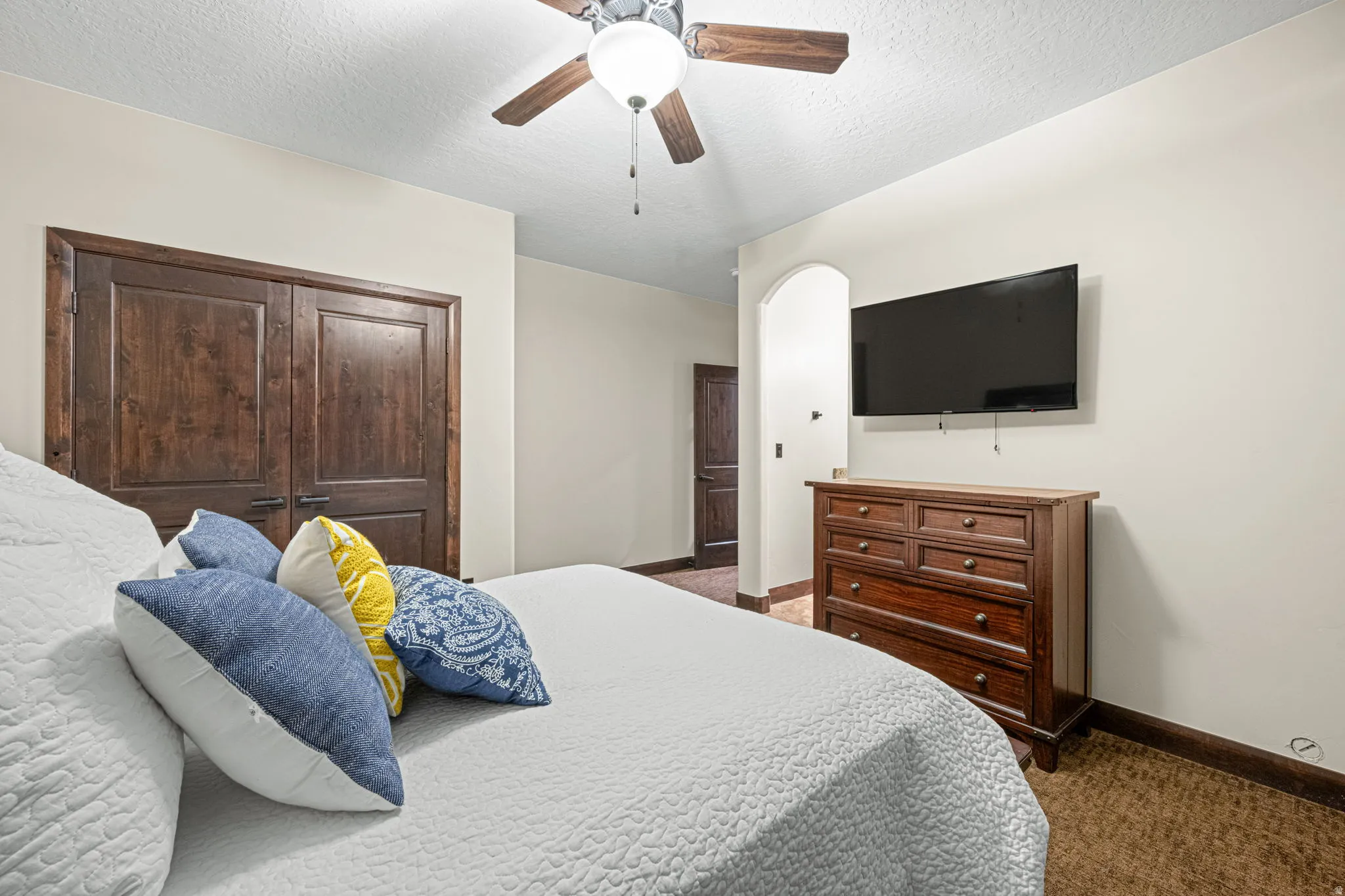 Bedroom featuring a closet, a textured ceiling, dark carpet, and a ceiling fan
