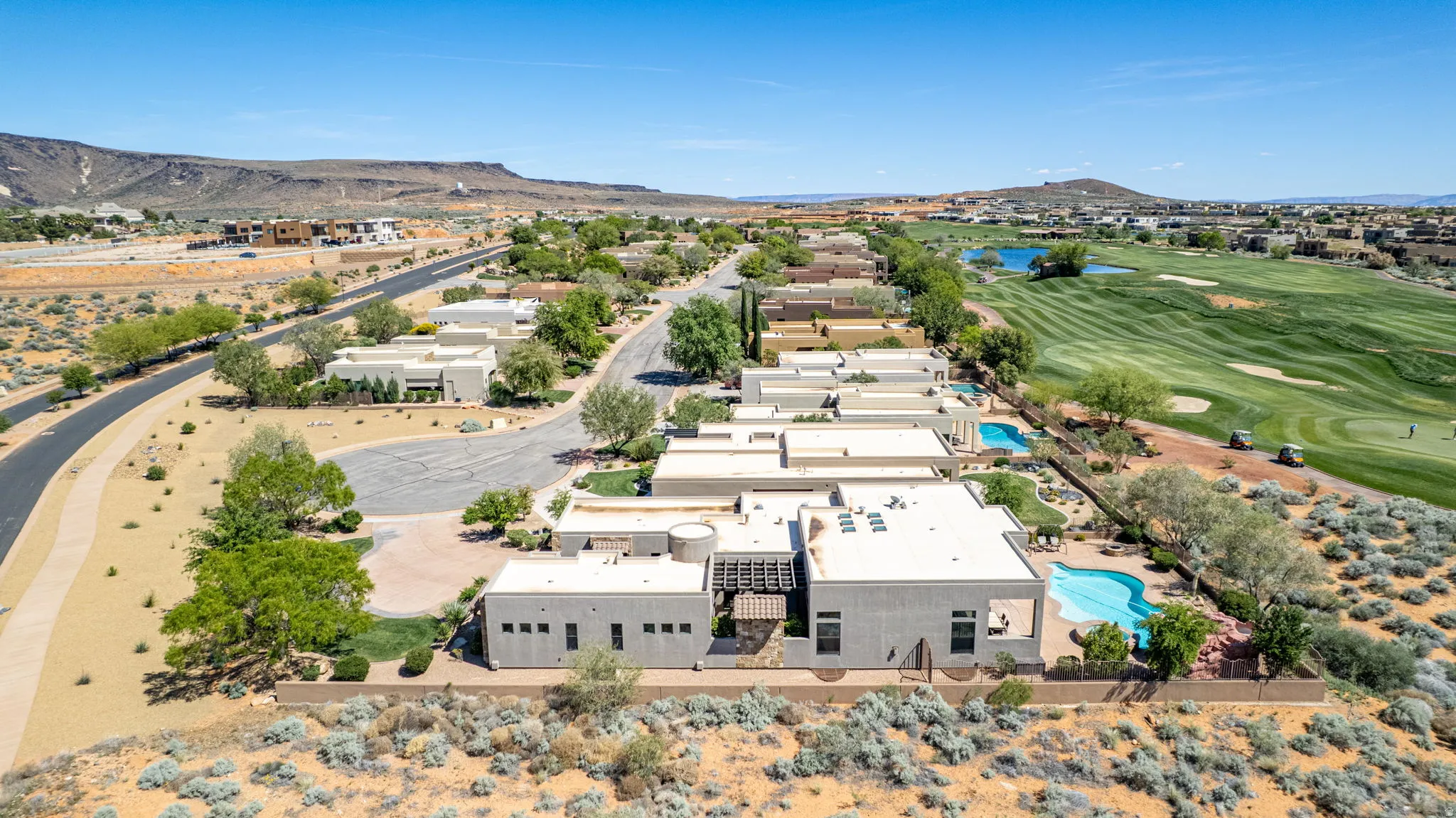 Aerial view of property and surrounding area with a golf course and a water and mountain view