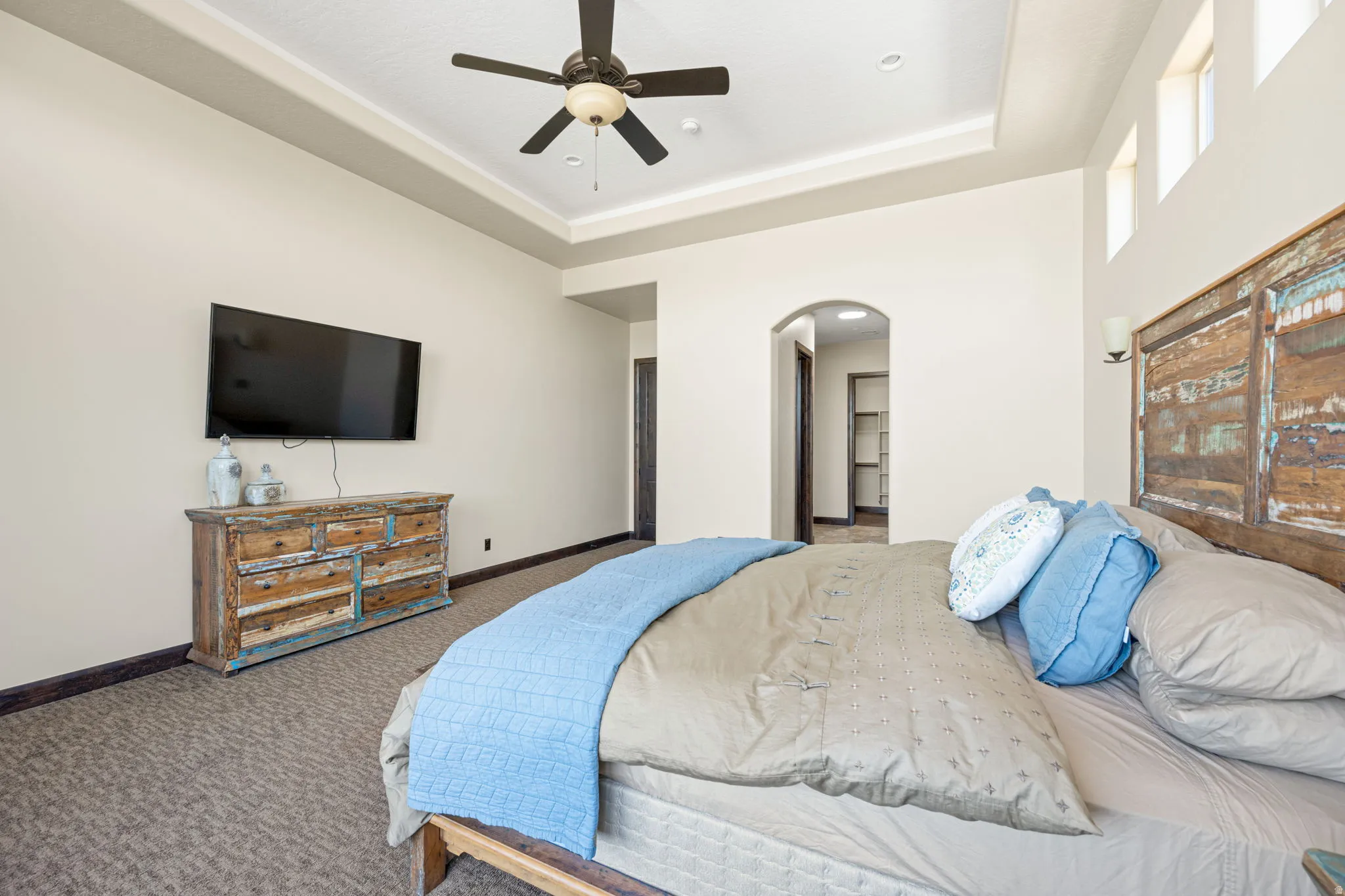 Bedroom featuring arched walkways, carpet flooring, a ceiling fan, recessed lighting, and a raised ceiling