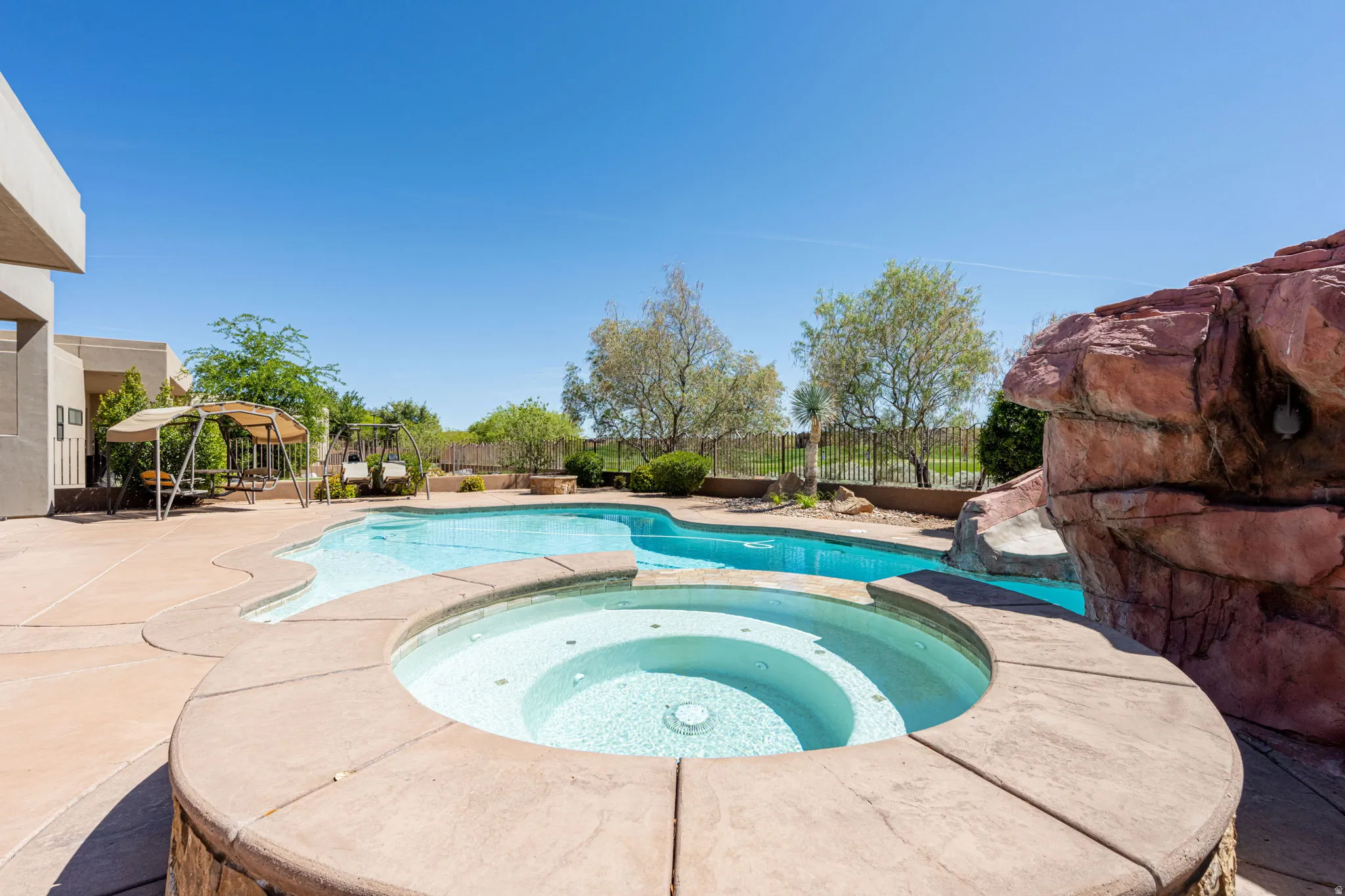 Combined pool / hot tub with a patio area and a fenced backyard