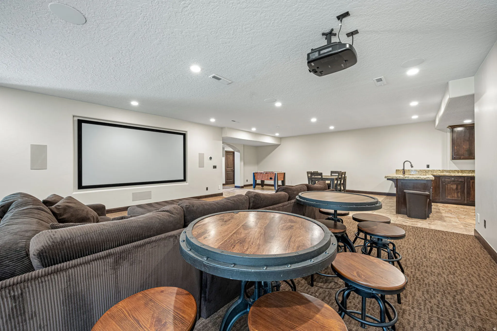 Home theater with a textured ceiling, arched walkways, and recessed lighting