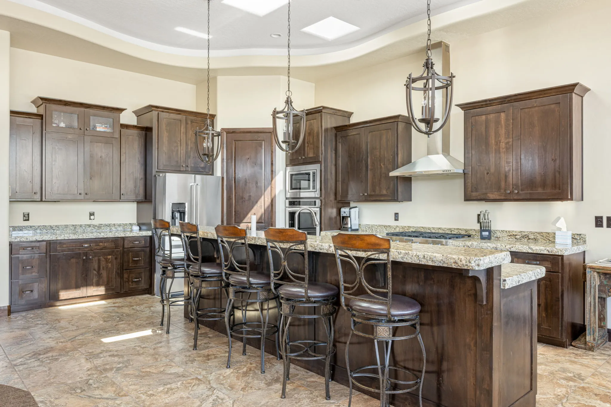 Kitchen with a kitchen bar, dark wood finish cabinetry, a raised ceiling, and stainless steel appliances