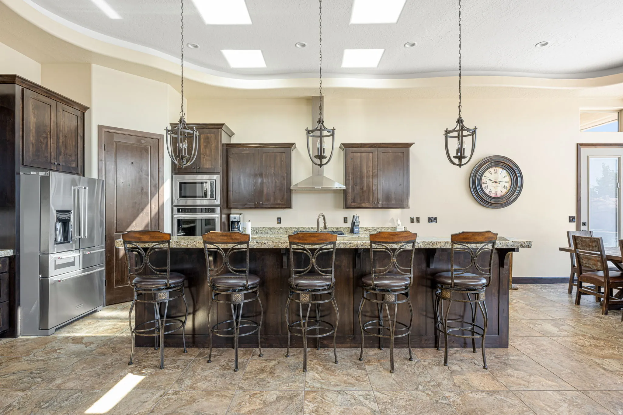 Kitchen with dark wood finish cabinets, a breakfast bar area, stainless steel appliances, light stone countertops, and a raised ceiling