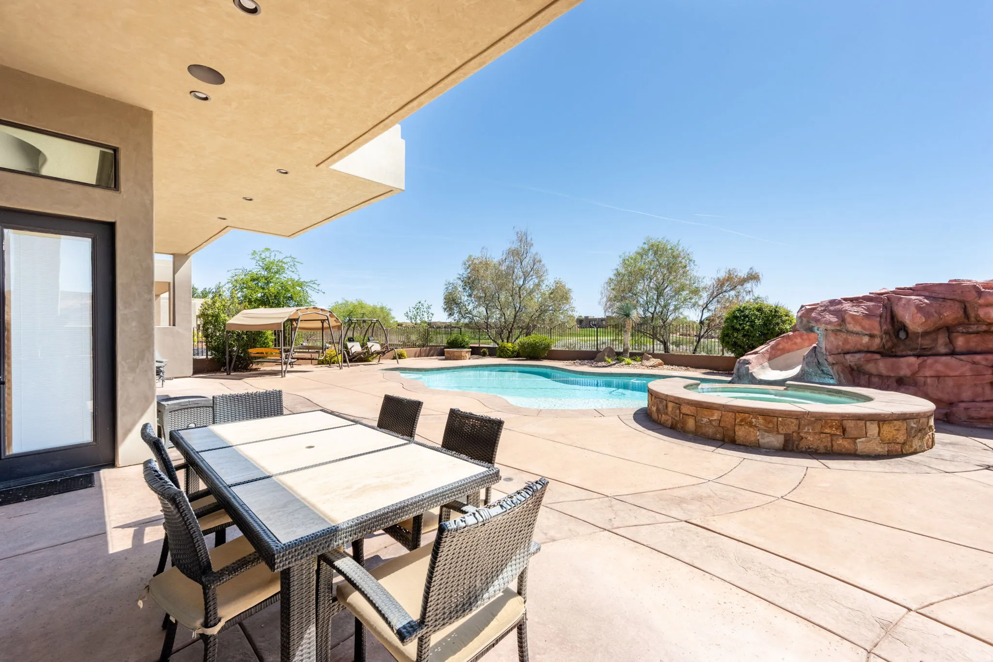 Integrated pool / hot tub with a patio, outdoor dining space, a fenced backyard, and a water slide