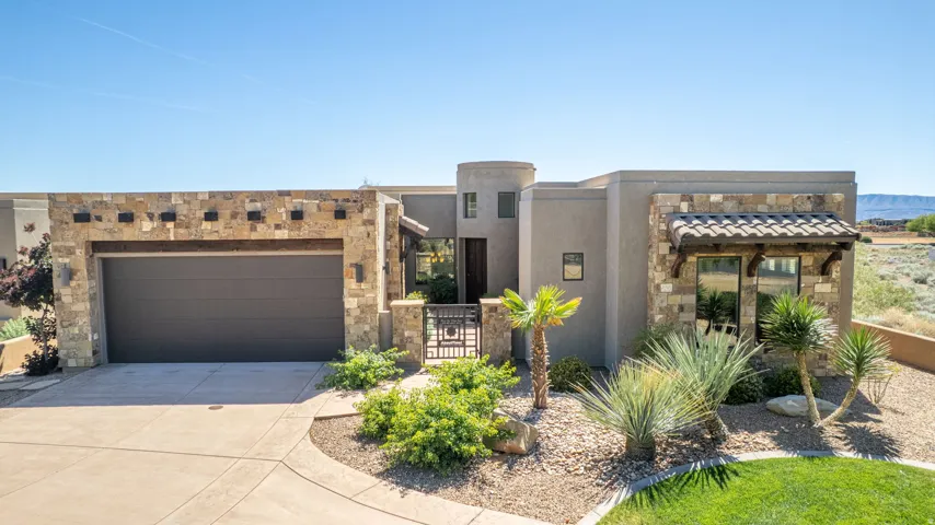 View of front of house with stone siding, driveway, a garage, and stucco siding