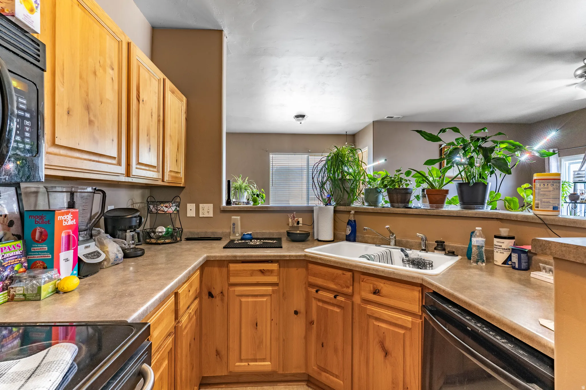 Kitchen featuring black appliances, light countertops, and light wood finish cabinetry