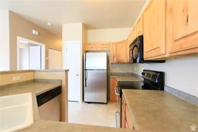 Kitchen featuring stainless steel appliances, light wood finish cabinets, light countertops, and light floors