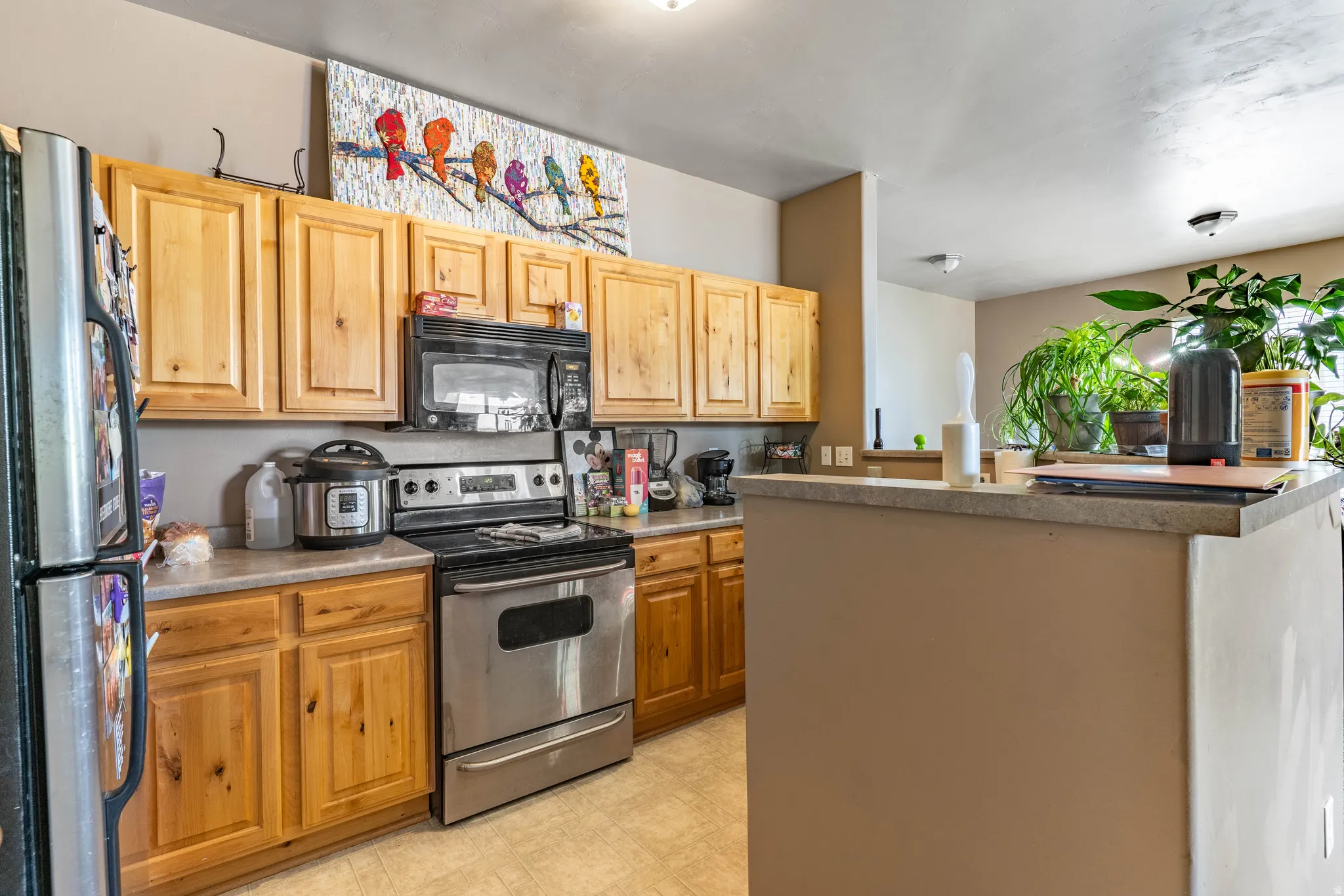 Kitchen featuring stainless steel appliances, a kitchen island, light floors, and light wood finish cabinets
