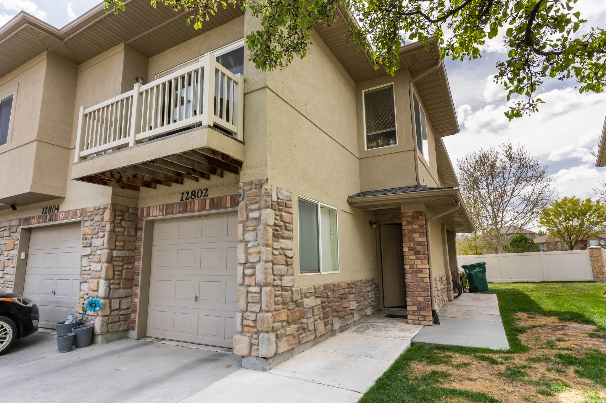 View of home's exterior with a balcony, stone siding, stucco siding, and an attached garage