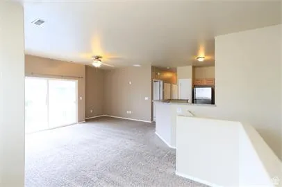 Unfurnished living room featuring carpet and ceiling fan