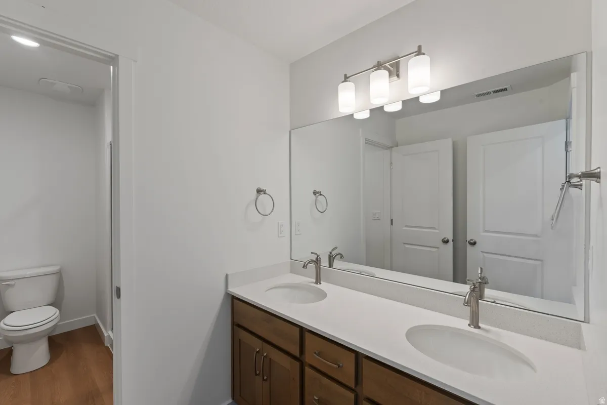 Full bath featuring double vanity and wood finished floors