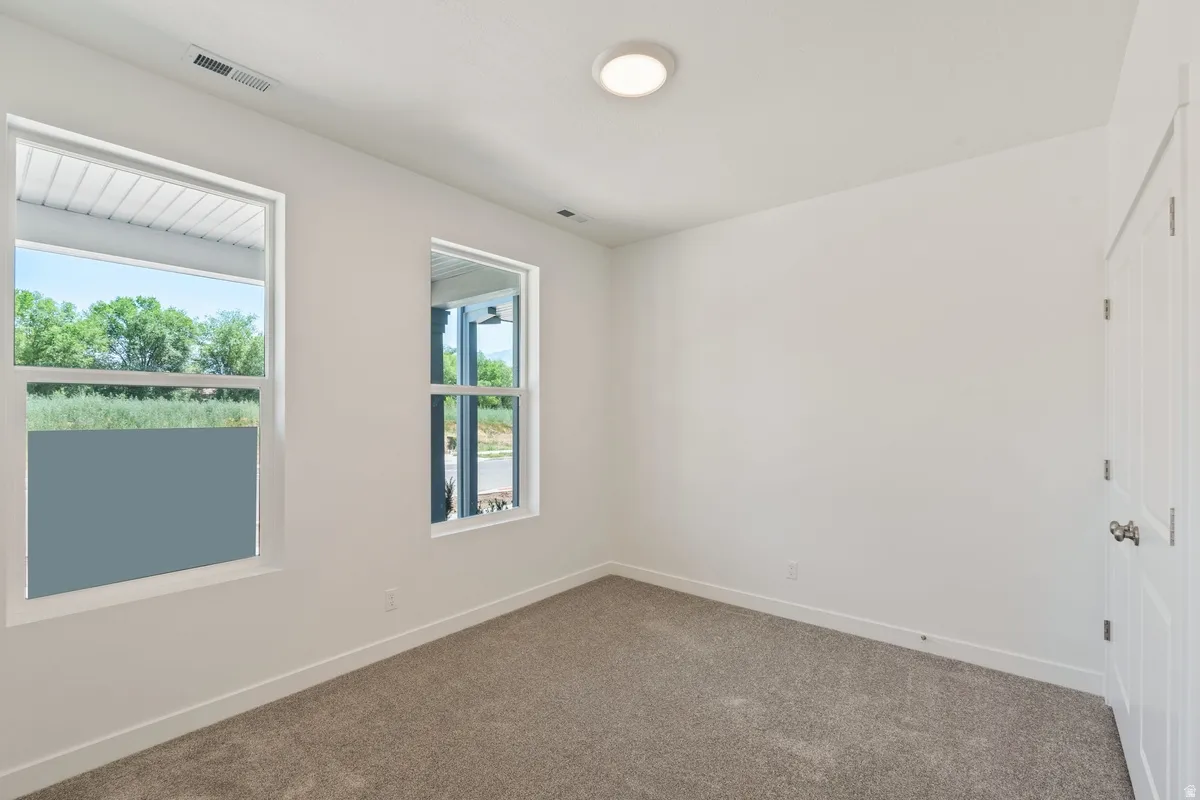 Unfurnished room featuring baseboards and dark carpet