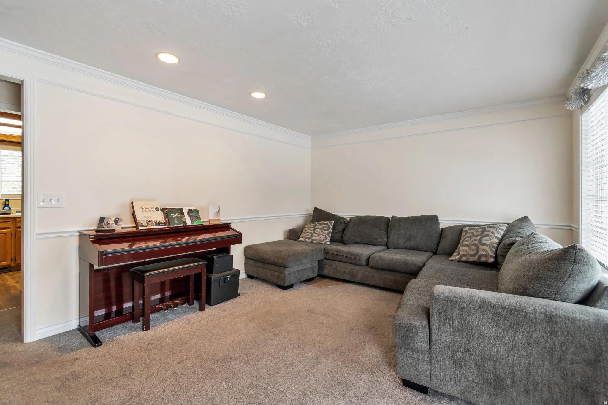 Living area with carpet floors, ornamental molding, and recessed lighting