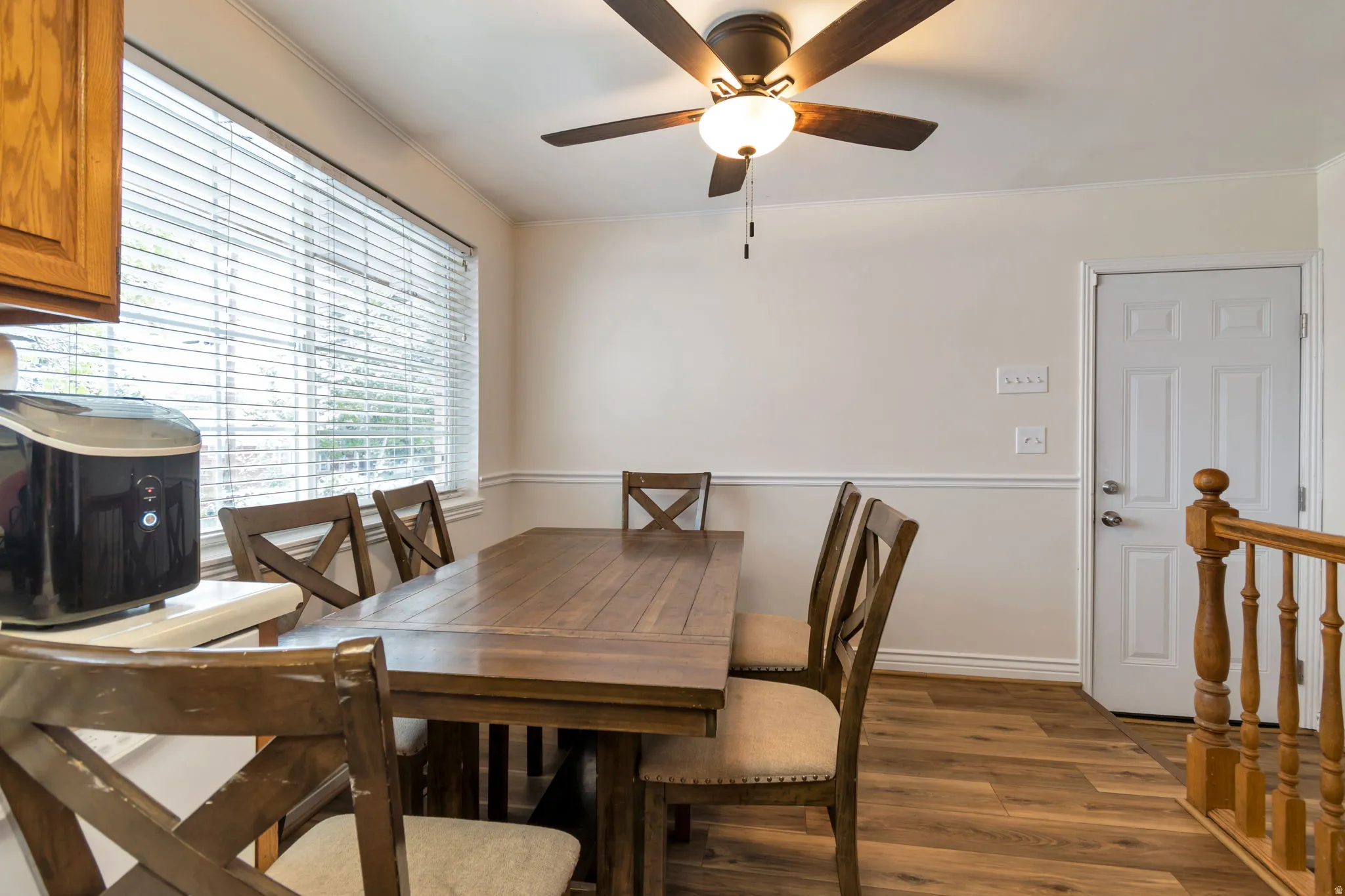 Dining room with dark wood-style flooring, crown molding, and ceiling fan