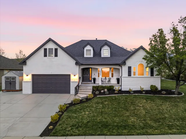 View of front of house featuring covered porch, brick siding, driveway, and stucco siding