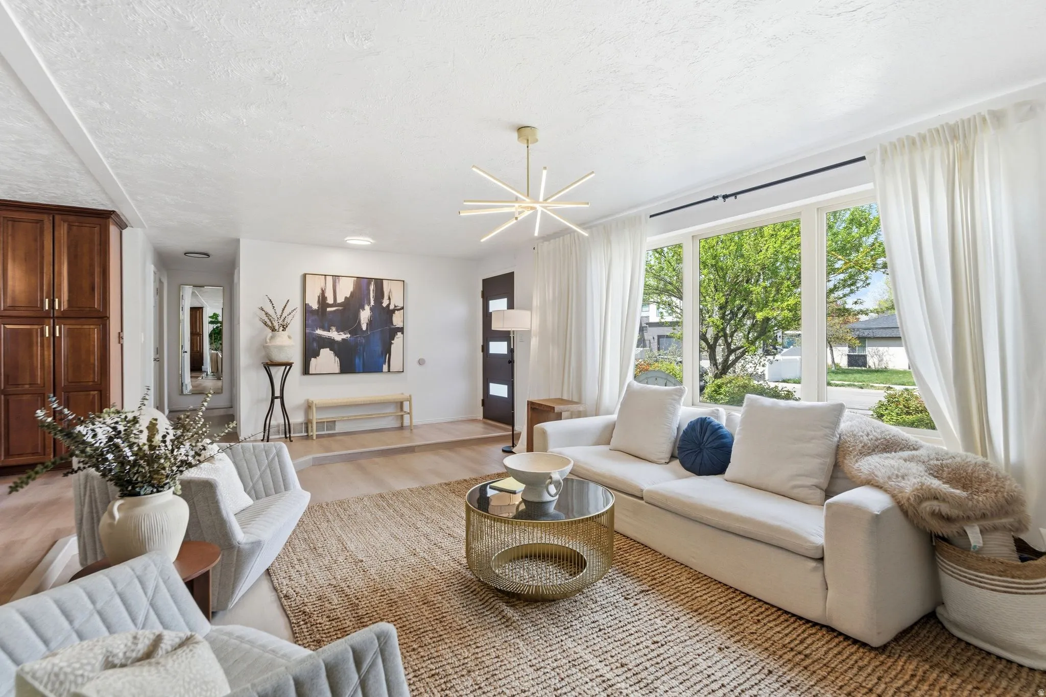 Living area with light wood-style floors, a textured ceiling, and hanging lights