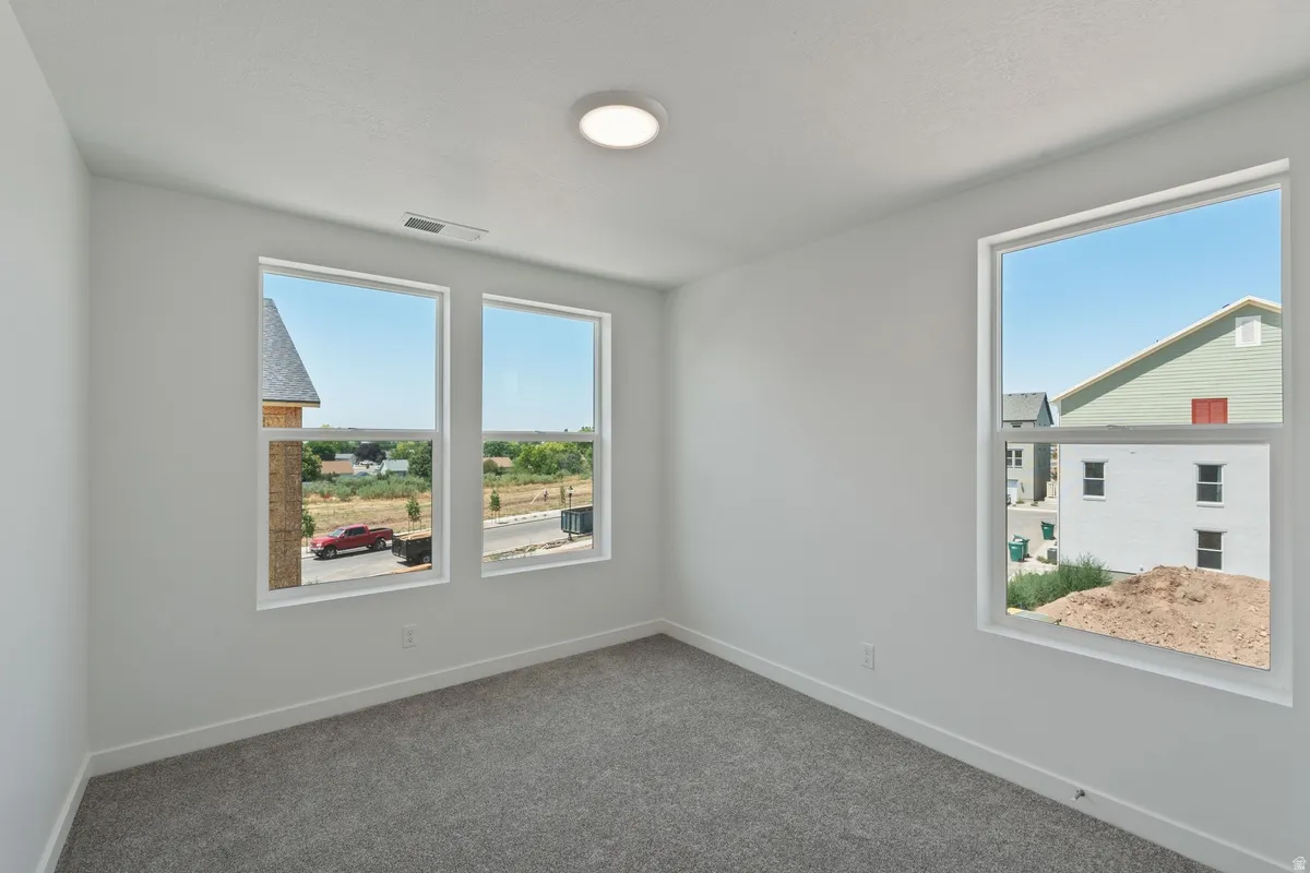 Unfurnished room featuring dark carpet and plenty of natural light
