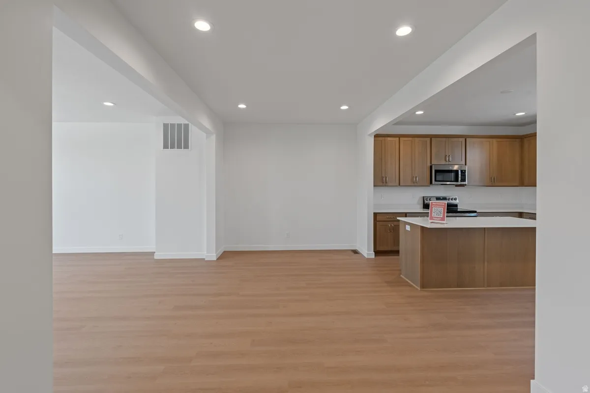 Kitchen featuring recessed lighting, light countertops, light wood finished floors, wood finish cabinetry, and stainless steel appliances