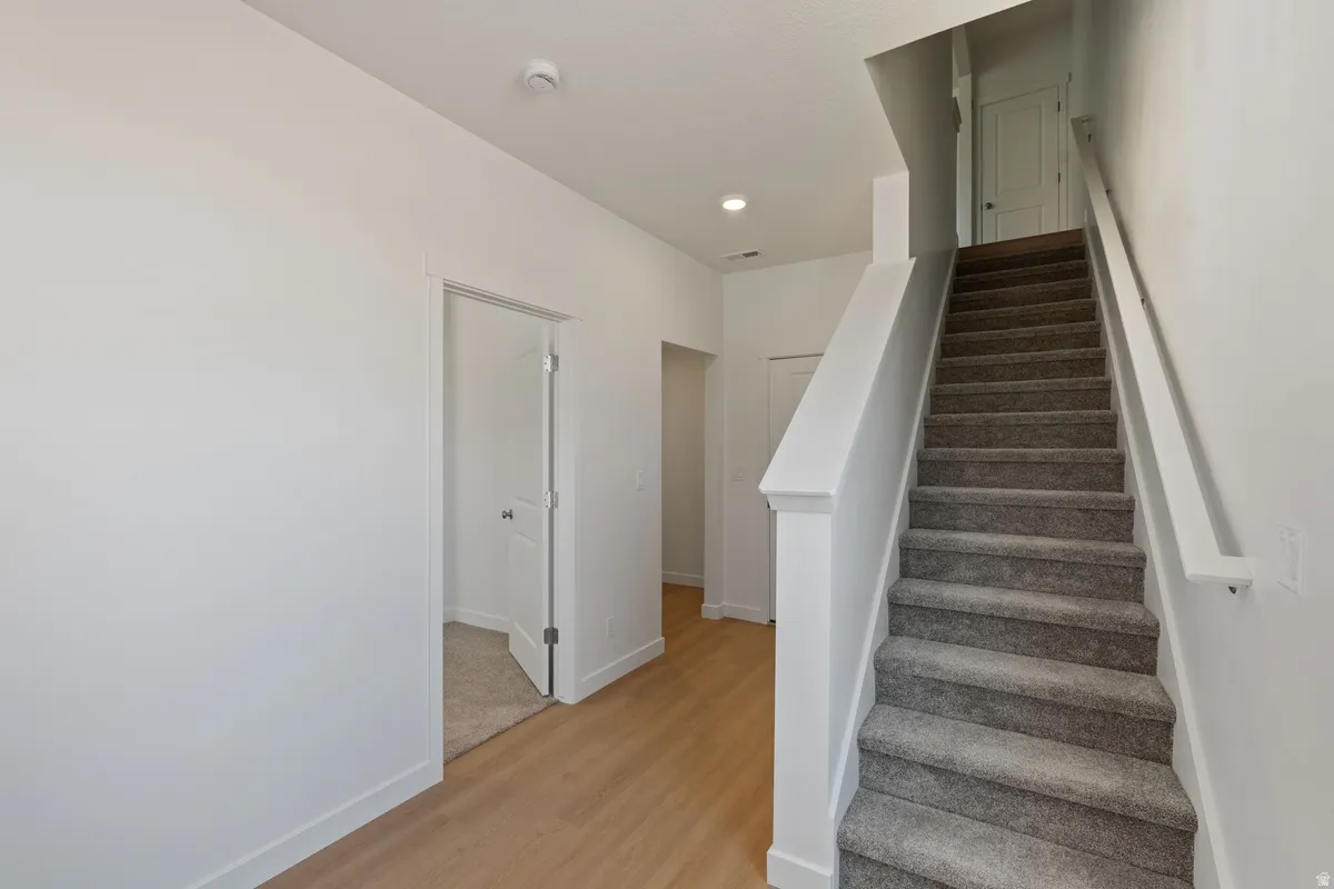 Stairway featuring wood finished floors and recessed lighting