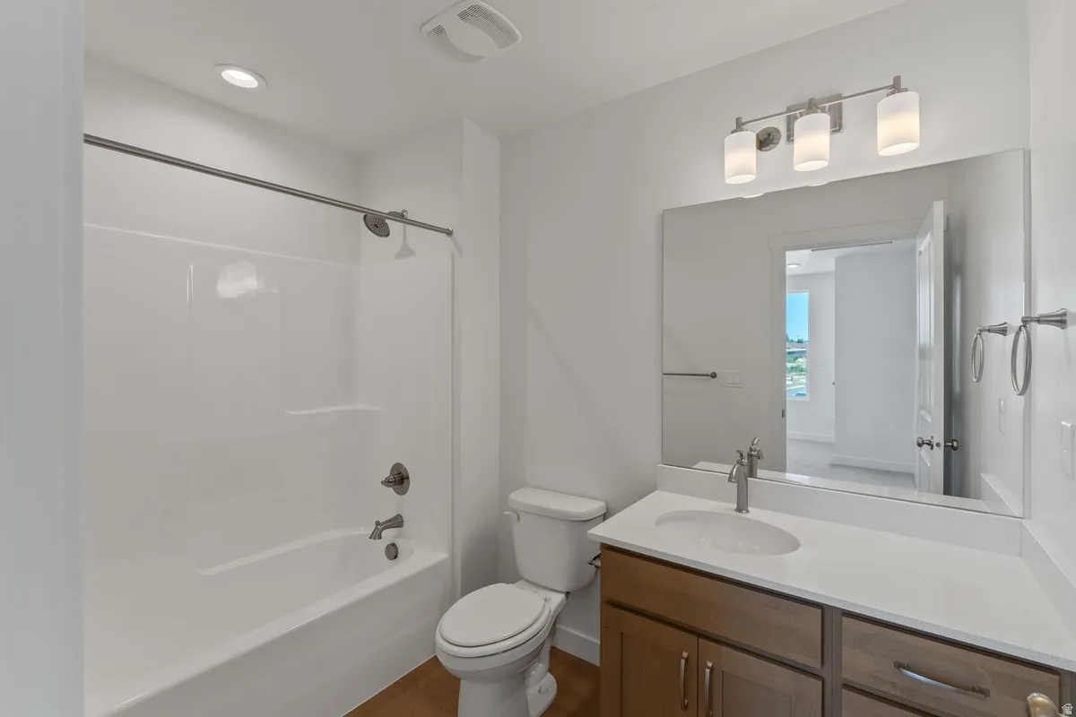 Full bath with vanity, tub / shower combination, dark wood-type flooring, and recessed lighting