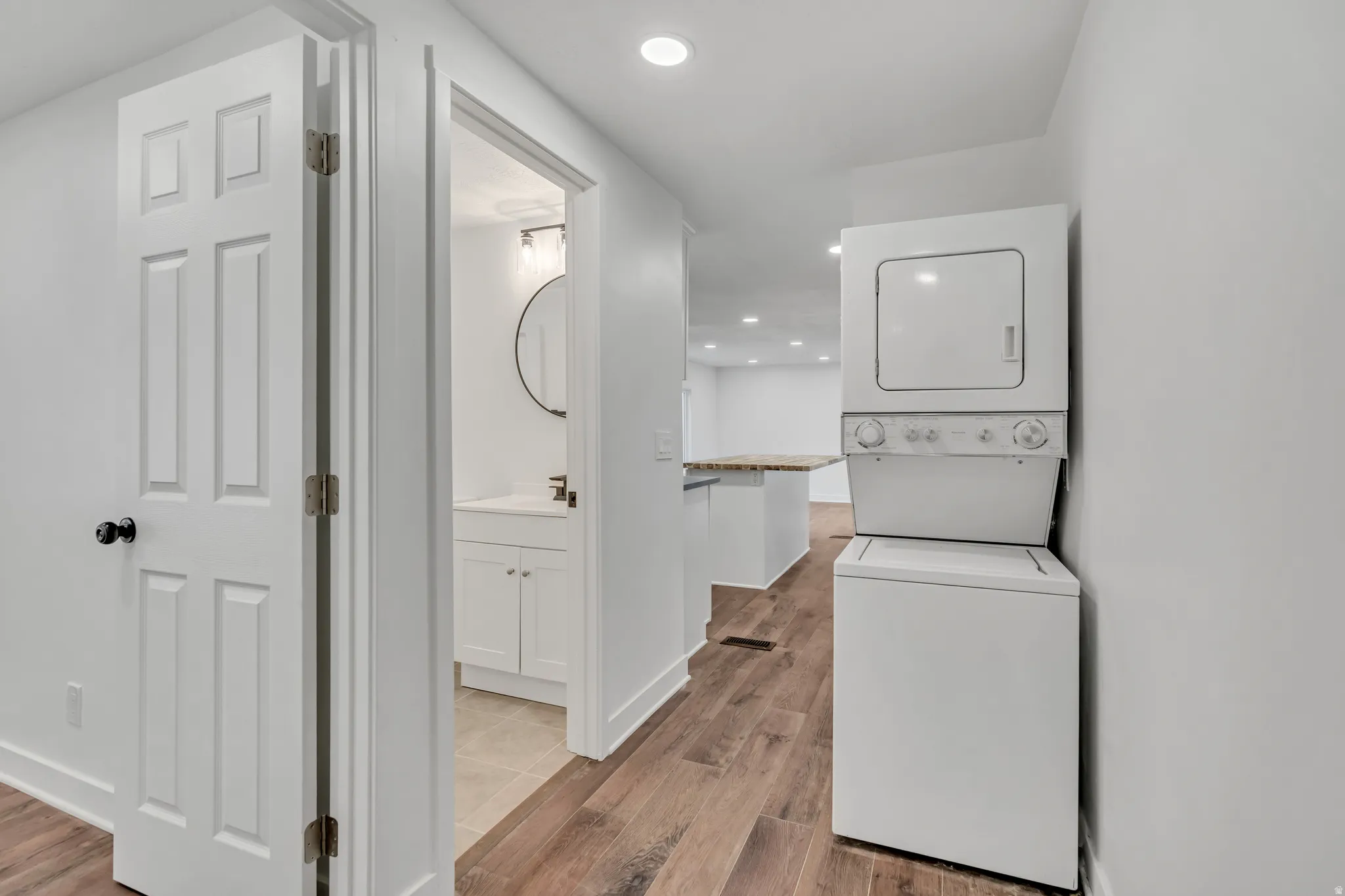 Laundry area featuring recessed lighting, light wood finished floors, and stacked washing machine and dryer