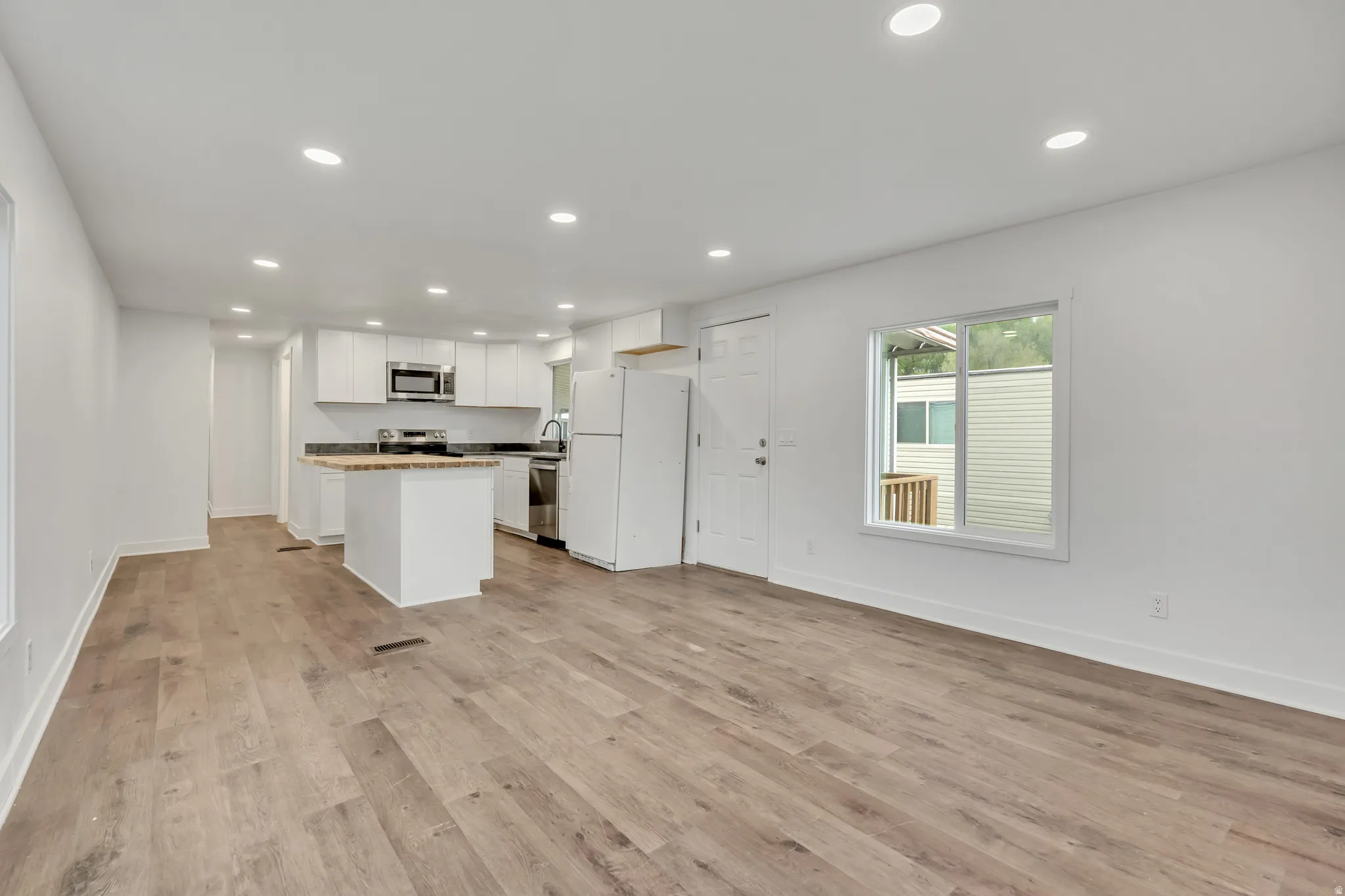 Kitchen with open floor plan, stainless steel appliances, recessed lighting, white cabinetry, and a kitchen island