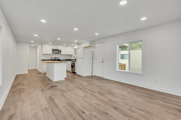 Kitchen with open floor plan, stainless steel appliances, recessed lighting, white cabinetry, and a kitchen island