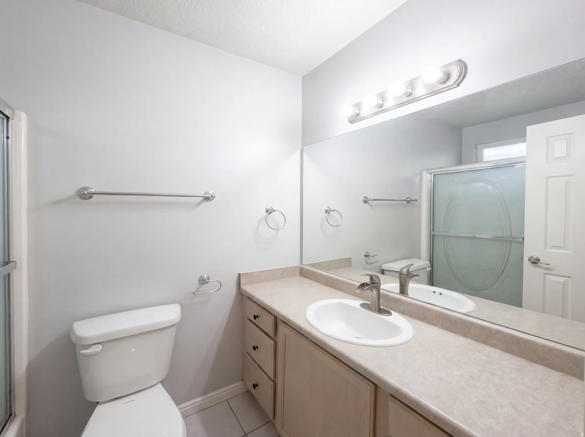 Full bath with a stall shower, vanity, and light tile patterned flooring
