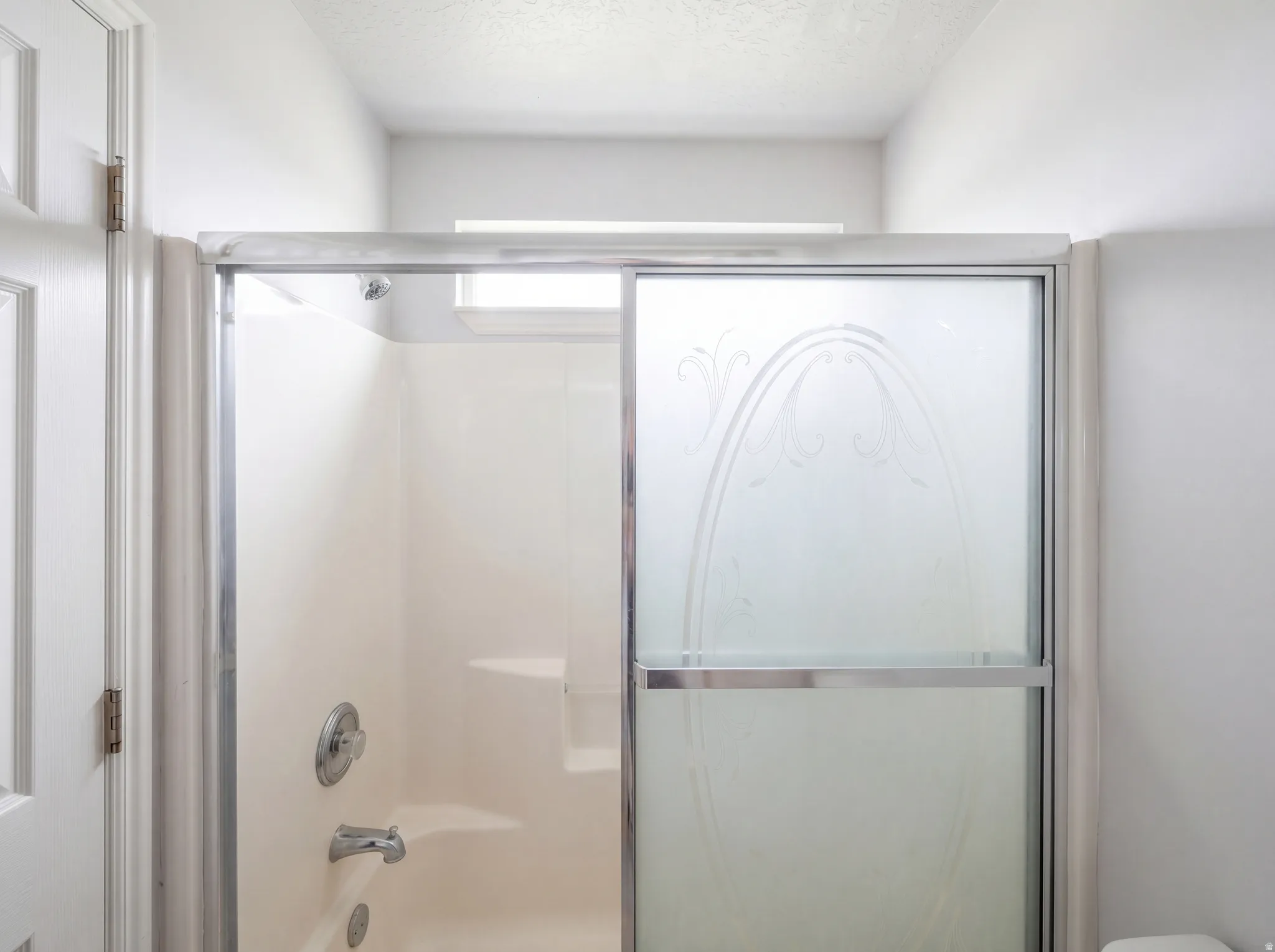 Full bath with a textured ceiling and enclosed tub / shower combo