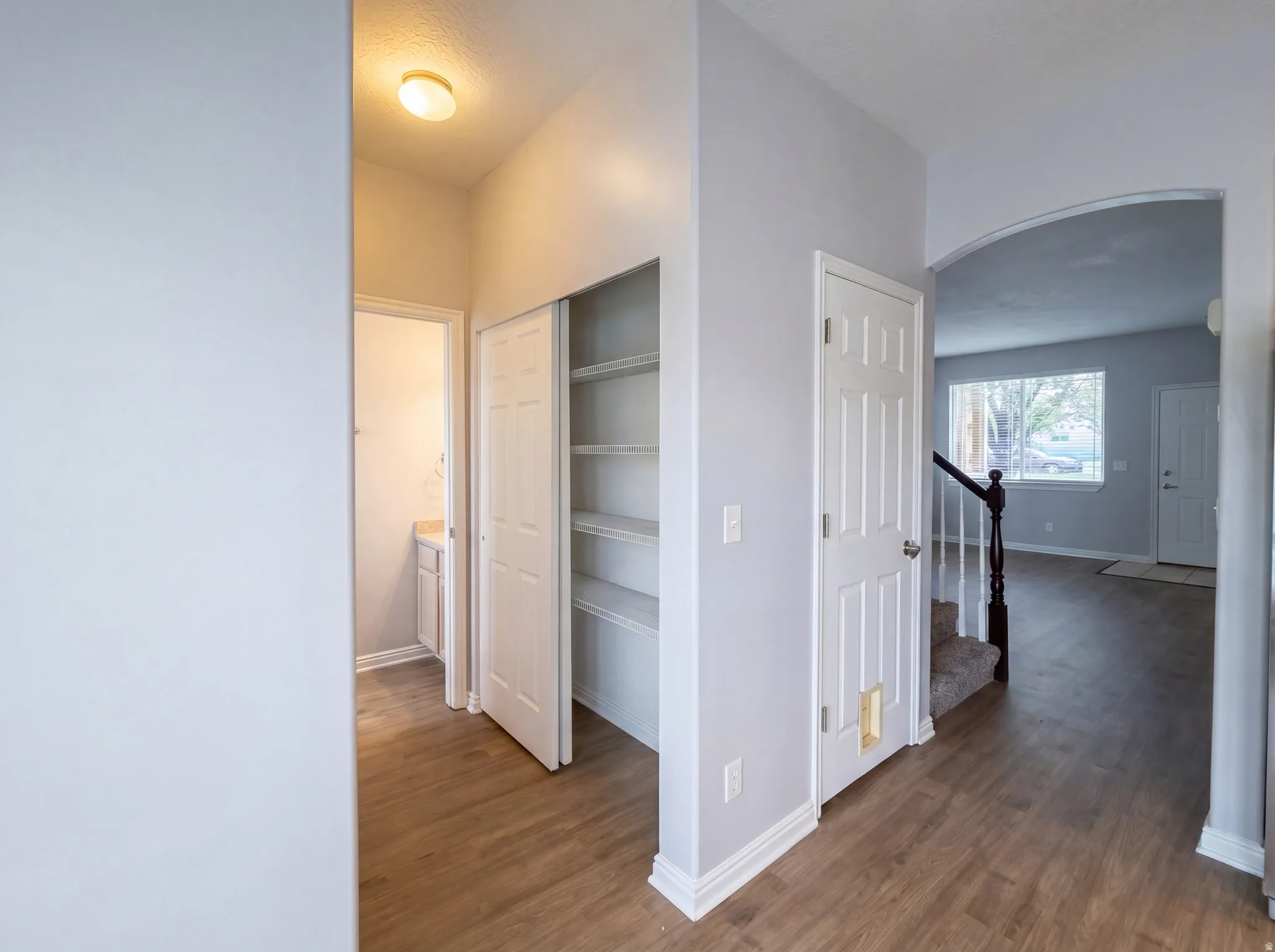 Hall featuring arched walkways and dark wood-type flooring